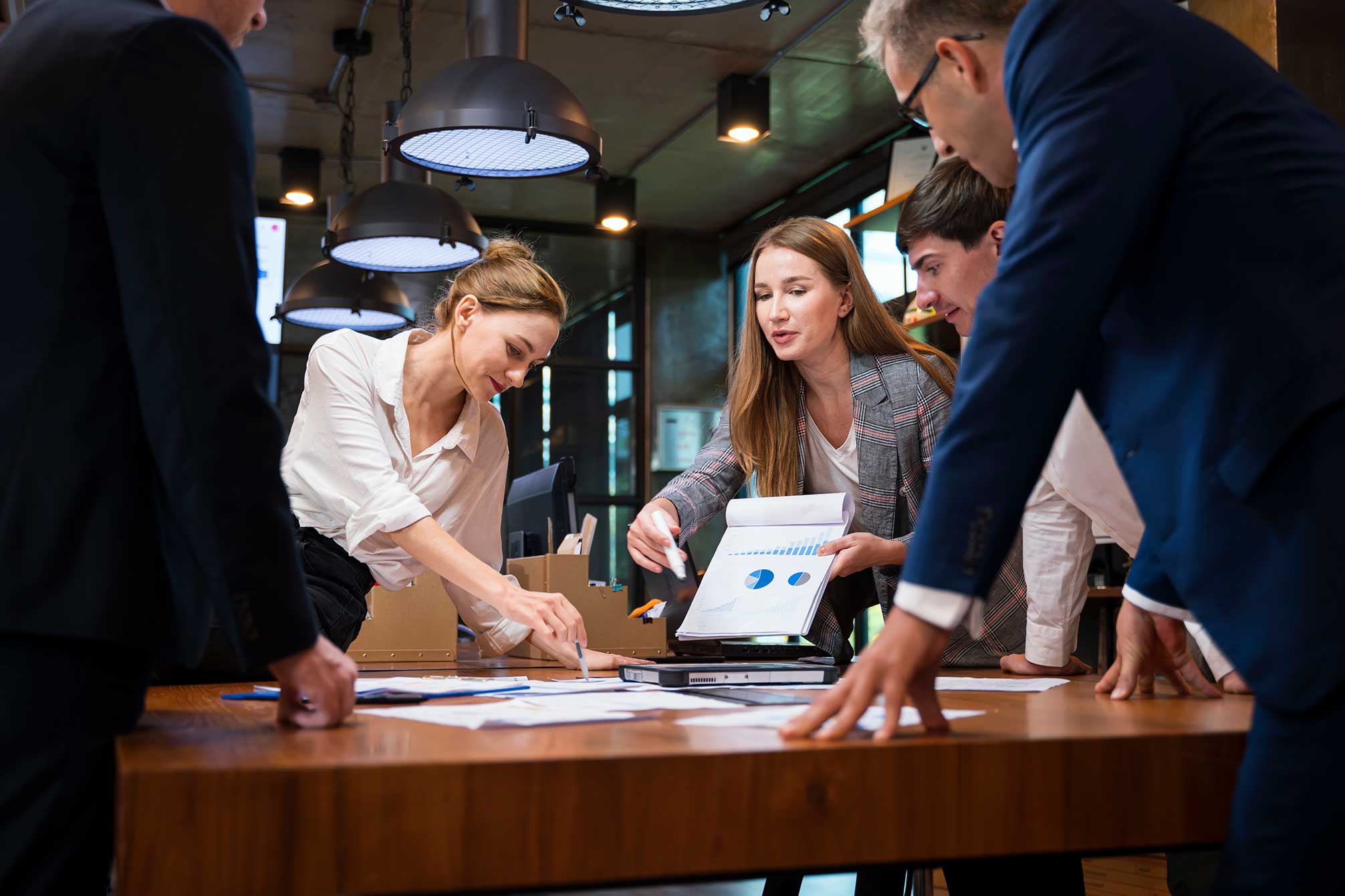 MOL-management five people standing around a desk working together to complete a project