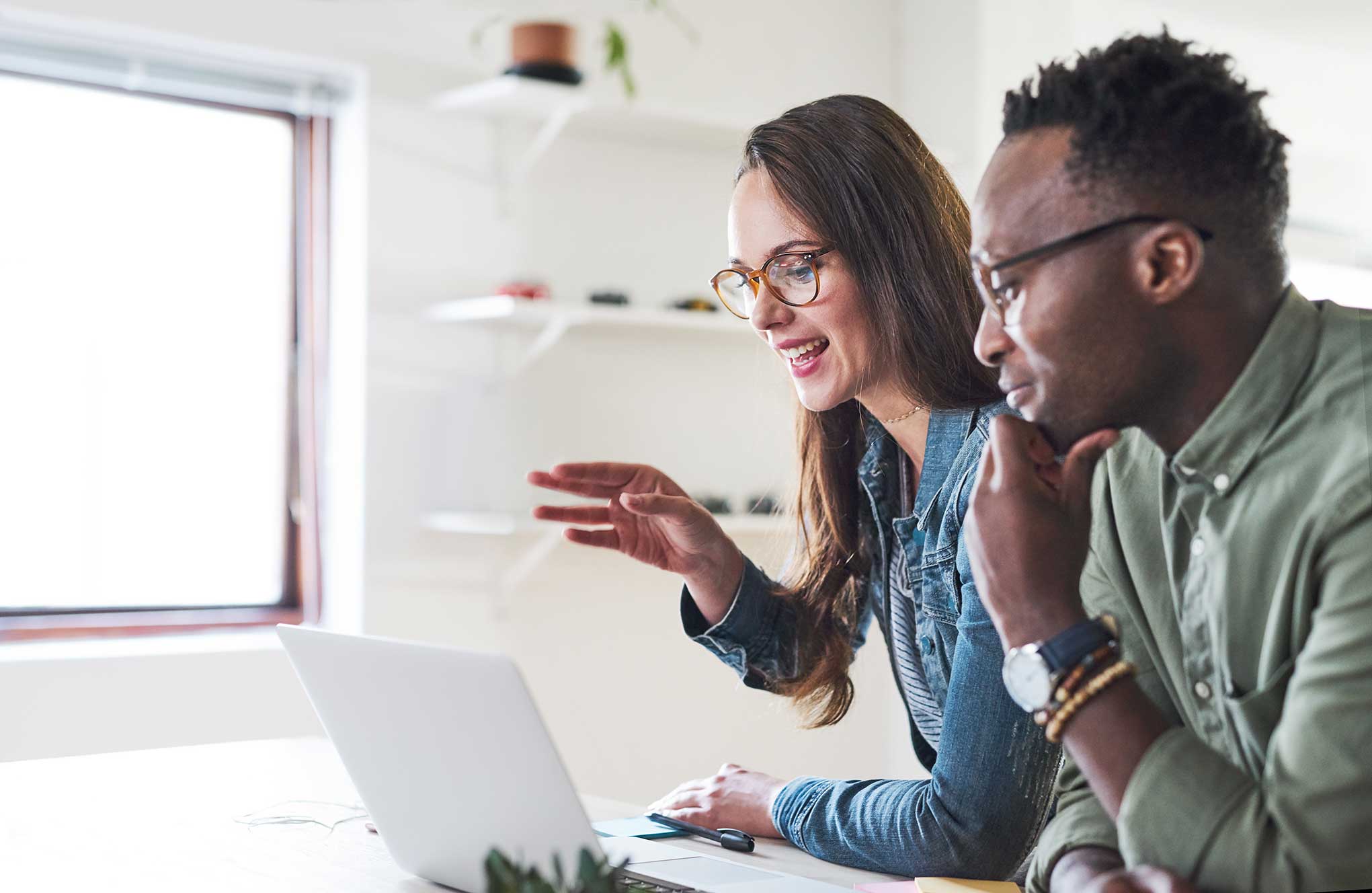 GettyImages-1179808218 two people having a conversation at a laptop in an office setting