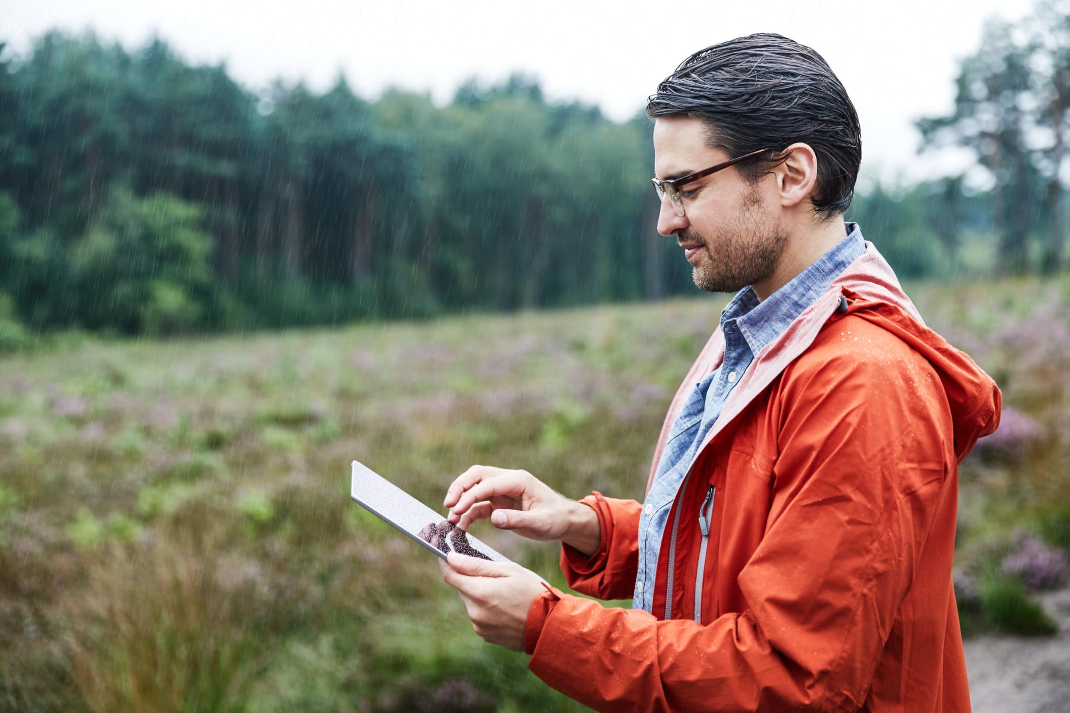 Man with tablet in landscape. a man standing in a large field of land is observing a tablet computer